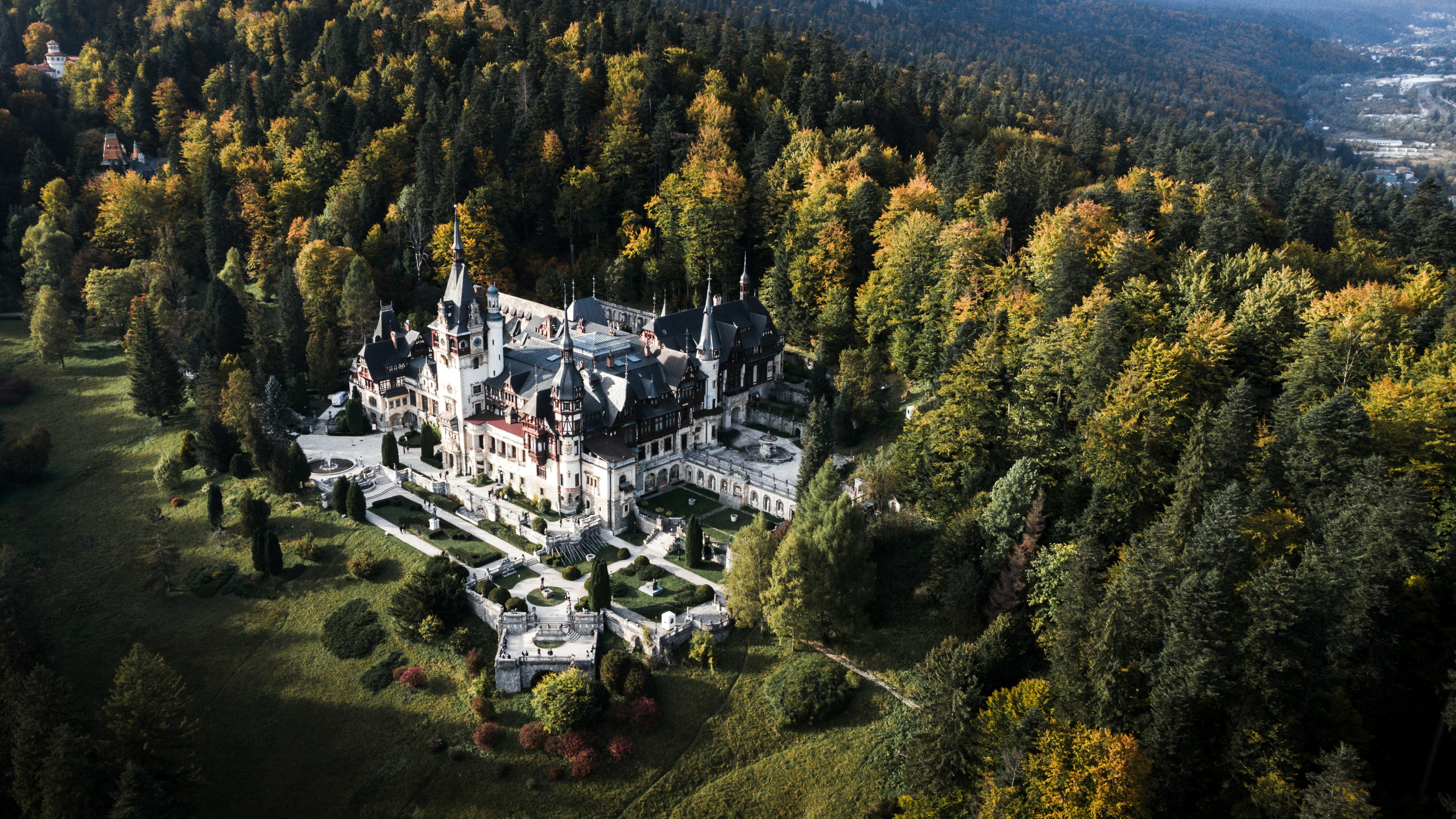 Il Castello di Peleș a Sinaia, Romania, con i tetti ripidi, i frontoni a graticcio e la foresta carpatica sullo sfondo.
