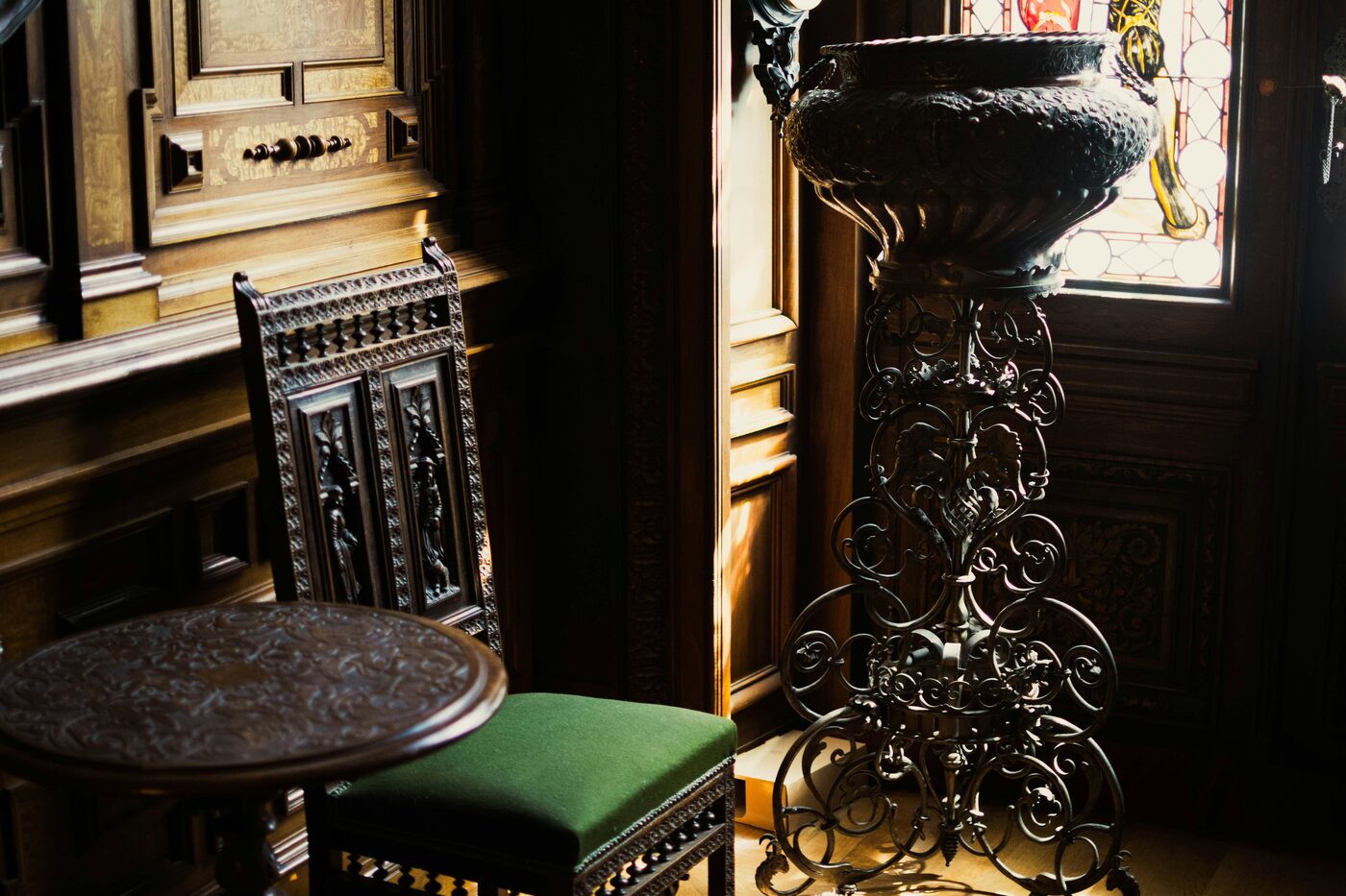 Una sala interna riccamente decorata del Castello di Peleș, con legno intagliato, dettagli ornamentali e arredi storici reali.
